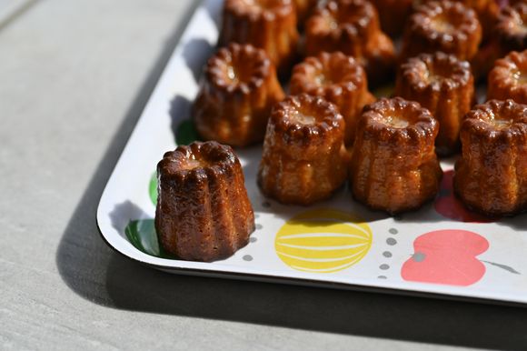 A tray of fresh Canelés, highlighting their dark golden color and shiny surface